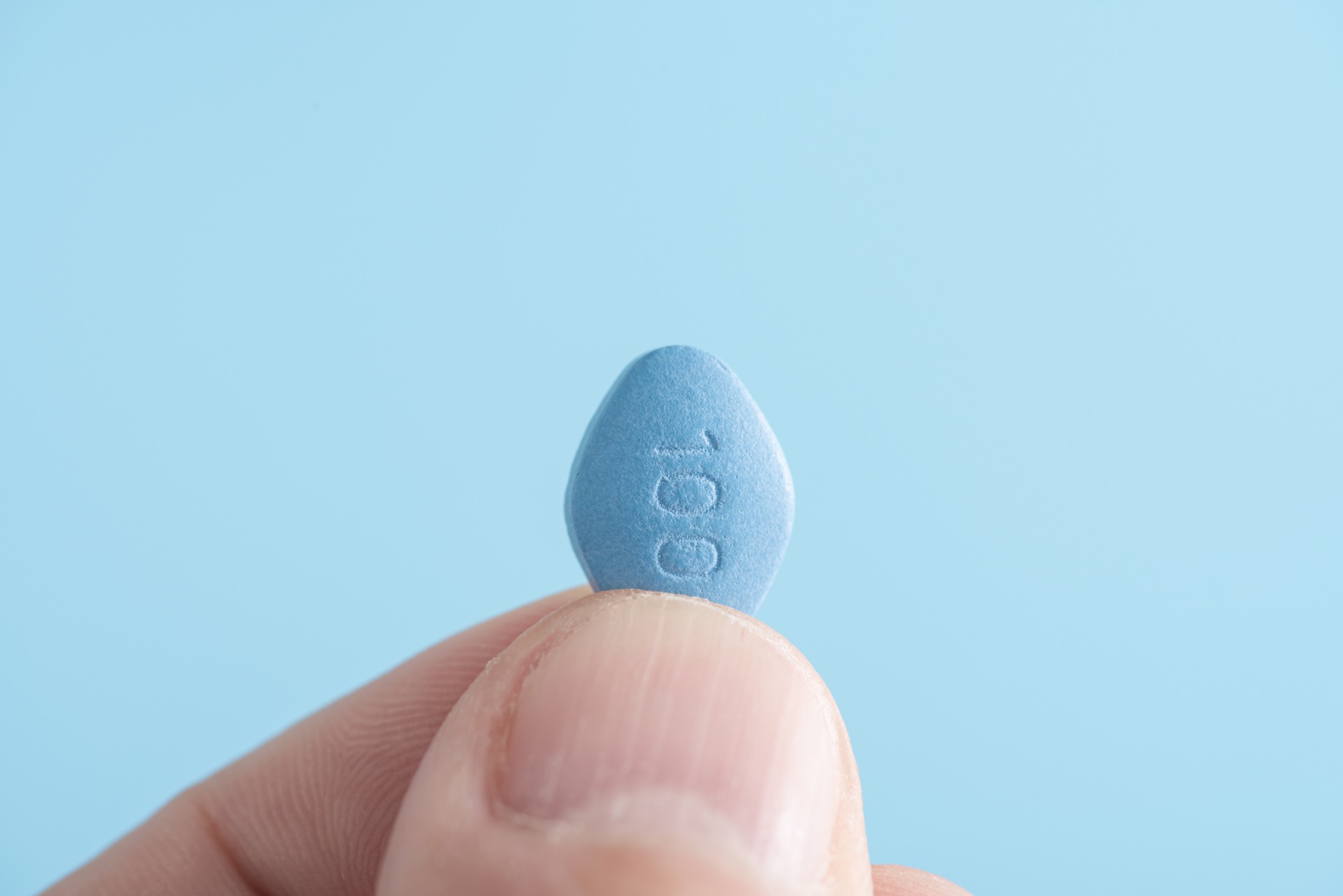 Man,Hold,Blue,Pill,Viagra,In,Fingers,On,Blue,Background